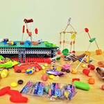 Image shows three candy structures, made with various types of gummy candy and toothpicks, on a table. Candy and candy packages are strewn across the table.